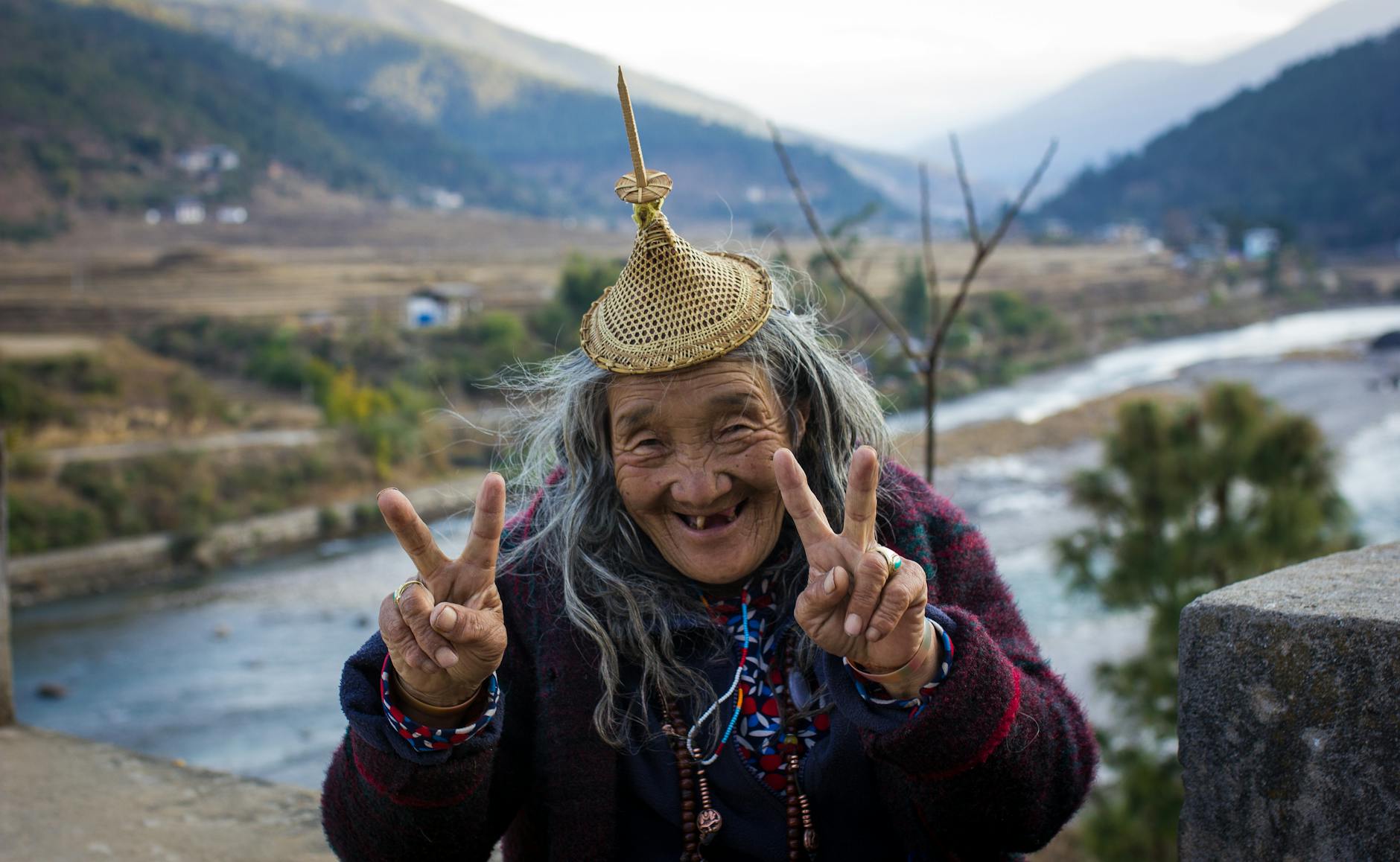 old ethnic woman showing v sign in countryside